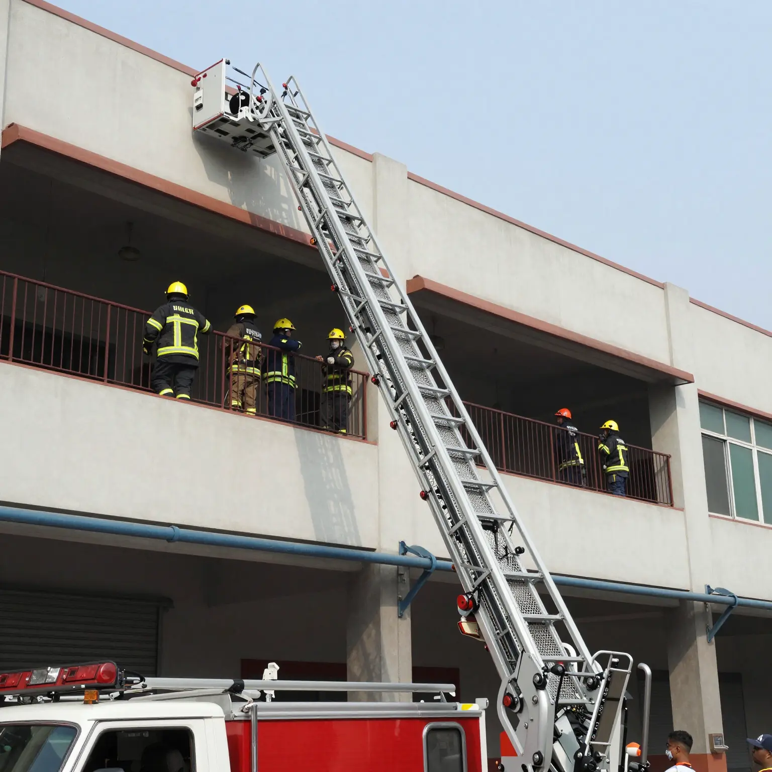 A fire truck ladder deployed at a commercial building, with firefighters accessing upper floors